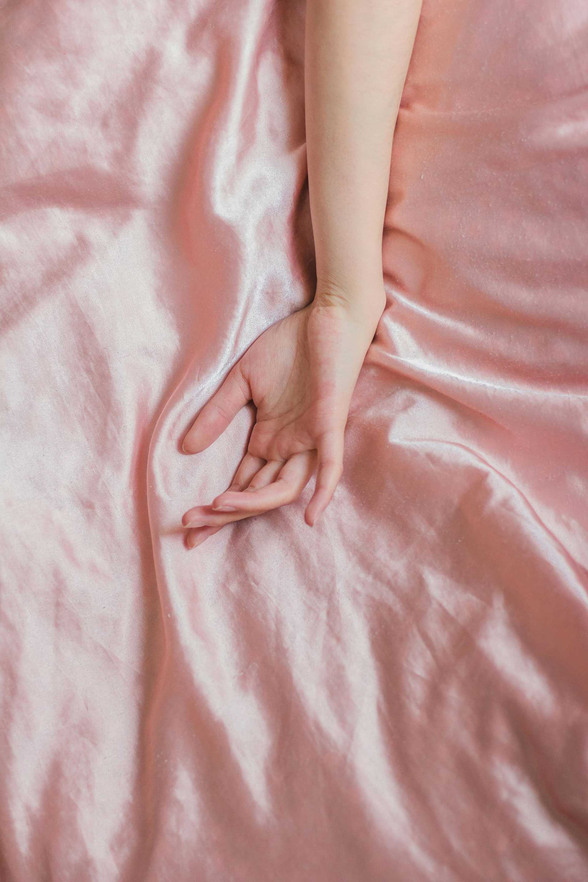 Hand resting on silky pink fabric.